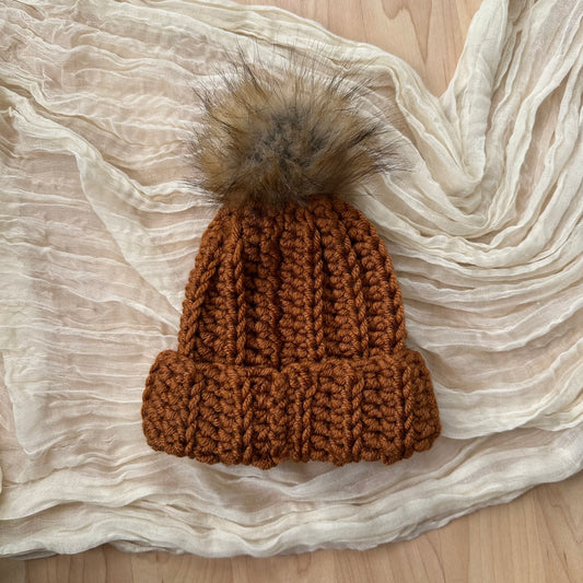Gorro de bebé color óxido con pompón de piel sintética