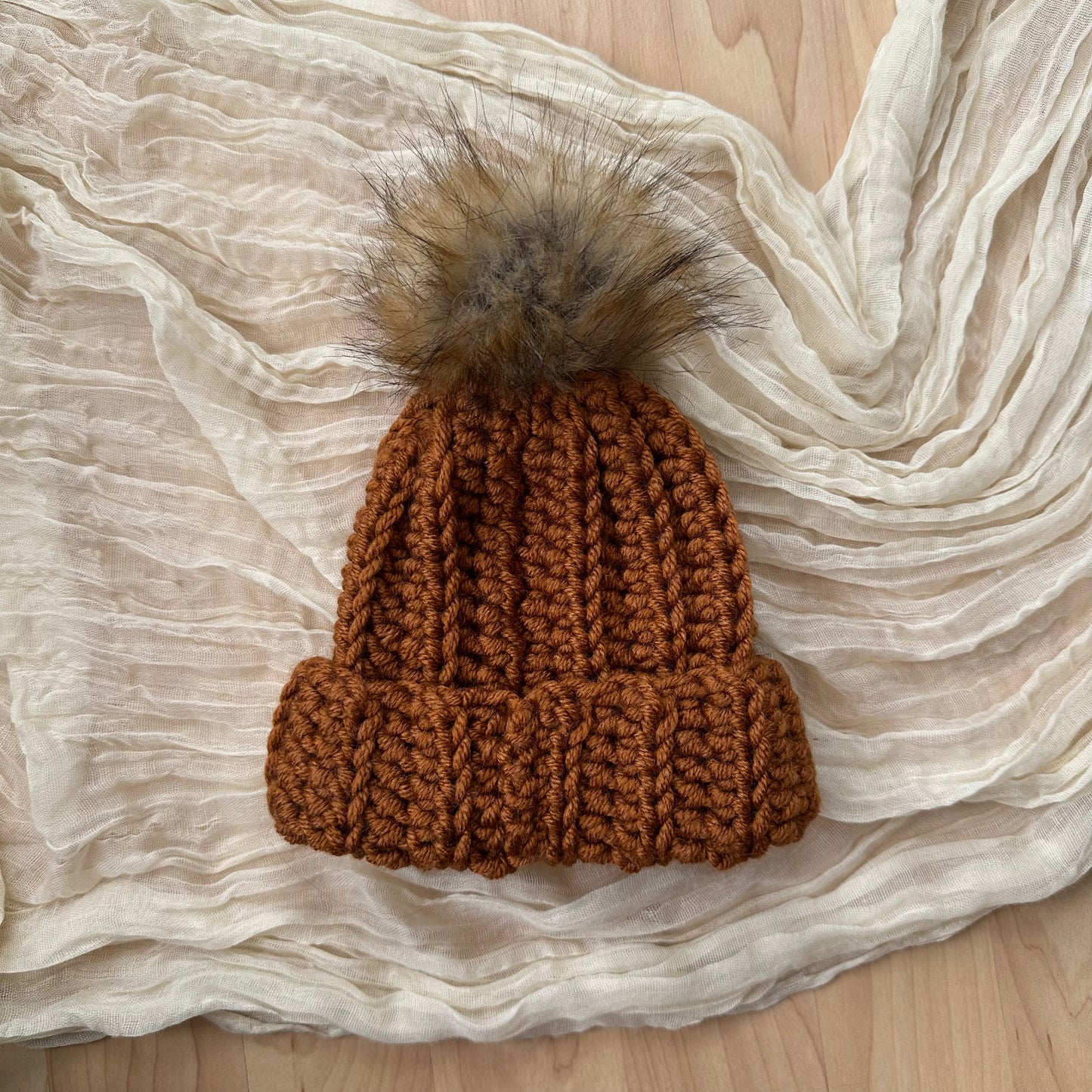 Gorro de bebé color óxido con pompón de piel sintética